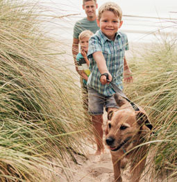 children walking dog on the beach