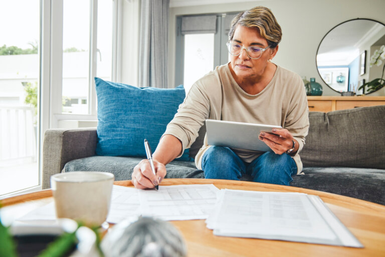 Shot of a mature woman using a digital tablet while going through paperwork at home avoiding conservatorship horizon elder law